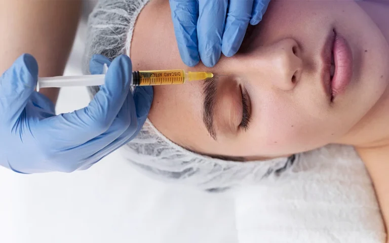 doctor holding mesotherapy needle over the young female patient's face