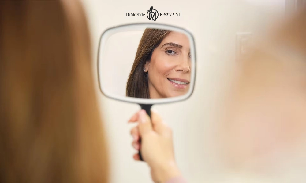 خانمی که در حال نگاه کردن به صورت خود در آینه است | درمان صورت نامتقارن